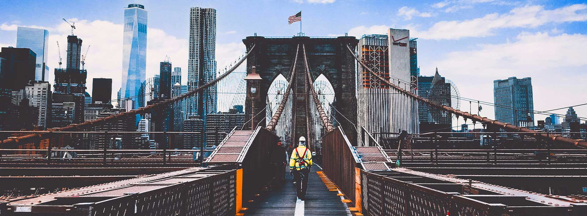 Labor studies department main image, show worker walking on a bridge with New York city in the background.