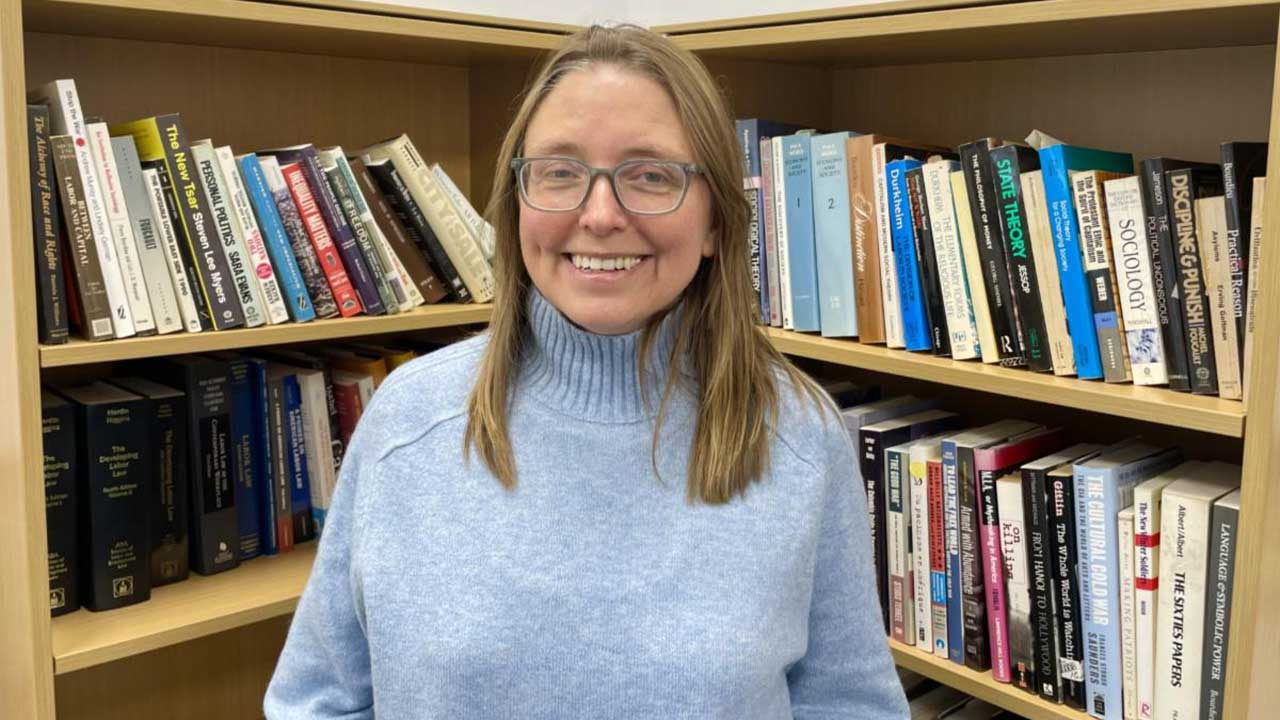 Ed Garcia Conde at SLU seated indoors in front of labor themed artwork